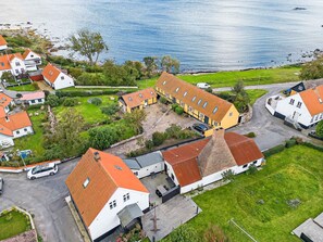 Een woongebied aan de kust, met huizen die rode dakpannen en witte muren hebben.