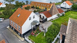 A coastal village with traditional houses, a prominent white building with a red roof, and a view of the sea. - 5 Star Holiday Home in Svaneke (Svaneke)