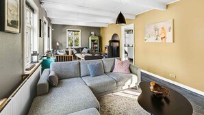 A modern living room with a sectional sofa, a fireplace, and a dining area. - 5 Star Holiday Home in Svaneke (Svaneke)