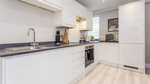 Una cocina moderna con armarios blancos, un lavamanos de acero inoxidable y un horno empotrado.