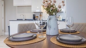 Una mesa de comedor dispuesta con platos, vasos y un florero en una cocina moderna.