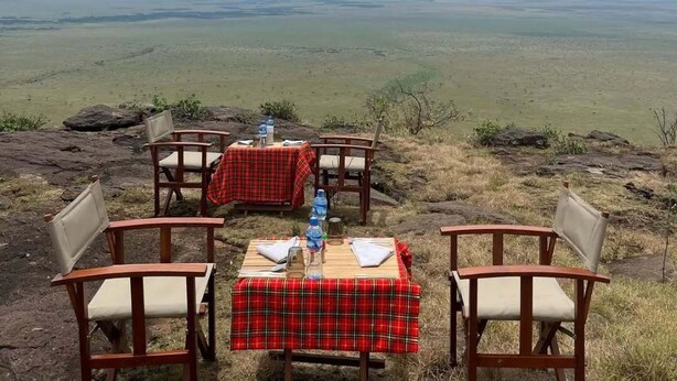 A table set on a rocky outcrop with a panoramic view of a vast landscape.