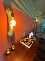 Una mesa de madera con una lámpara, un espejo y una bandeja con comida y bebidas.