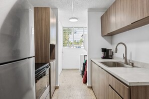 Eine moderne Küche mit Edelstahlgeräten, Holzschränken und einem Fenster, das für natürliches Licht sorgt.