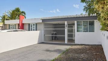 A modern building with a gated entrance, a red accent wall, and a paved driveway.
