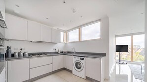 Une cuisine moderne équipée d’un lave-linge, d’une grande fenêtre et d’un téléviseur à écran plat.