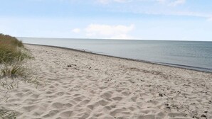A sandy beach with gentle waves and a clear sky. - 5 Star Holiday Home in Dannemare (Dannemare)