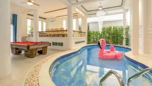A swimming pool with a pink flamingo float, a pool table, and a ceiling fan. - Lux white villa 9 Bedrooms (Ho Chi Minh City)