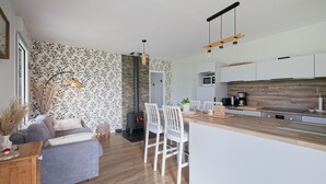 A modern kitchen with a central island, white chairs, a built-in oven, and a wooden countertop. - Les Gîtes de la Morinière - Brocéliande: The Little House on the Prairie (Neant sur Yvel)