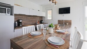 A modern kitchen with white cabinets, a wooden countertop, a built-in microwave, a coffee maker, and a TV mounted on the wall. - Les Gîtes de la Morinière - Brocéliande: The Little House on the Prairie (Neant sur Yvel)