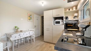 A compact kitchen with a microwave, oven, coffee maker, and a small dining area with a table and chairs.