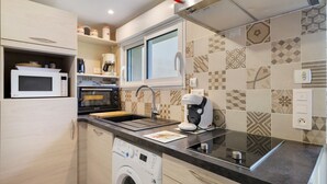 A compact kitchen with a microwave, oven, Bosch coffee machine, and a washing machine.