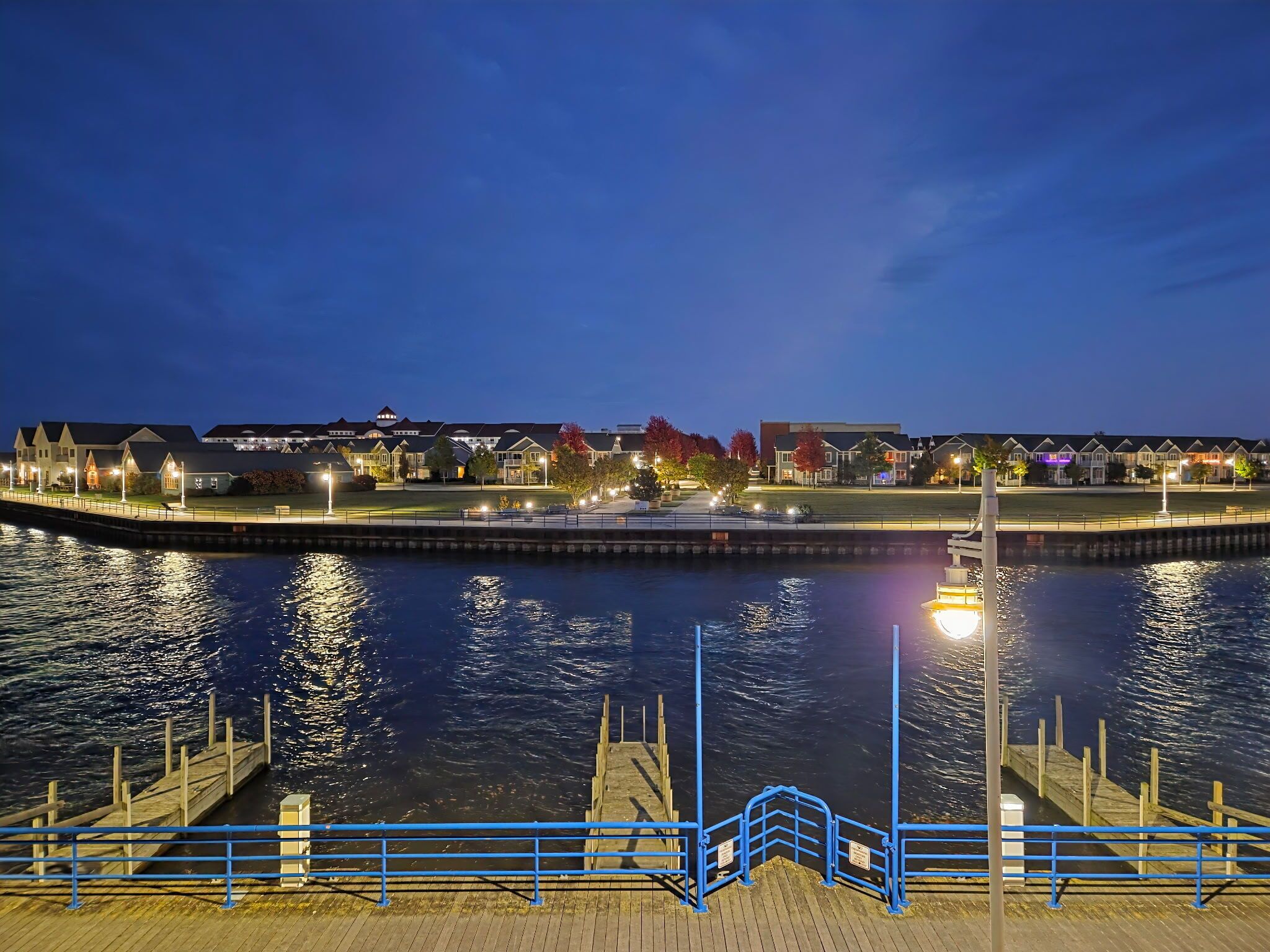 Un hôtel situé au bord de l’eau, doté d’un quai, de bâtiments illuminés et donnant sur une étendue d’eau calme.