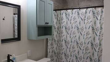 A bathroom with a white sink, a mirror, a light blue cabinet, and a floral shower curtain.