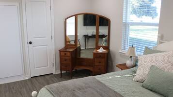 A bedroom with a bed, a dresser, a mirror, a window, and a door.