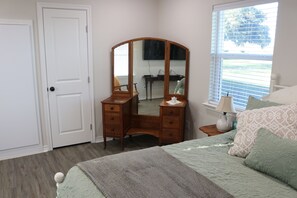 A bedroom with a bed, a dresser, a mirror, a window, and a door. - Charming Little Ranch House in Cook’s Pt - perfect for any Aggie Event! (Caldwell)