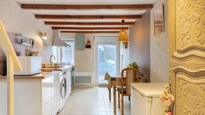 Een kleine keuken met een wasmachine, een spoelbak en een eethoek met een stoel en tafel.