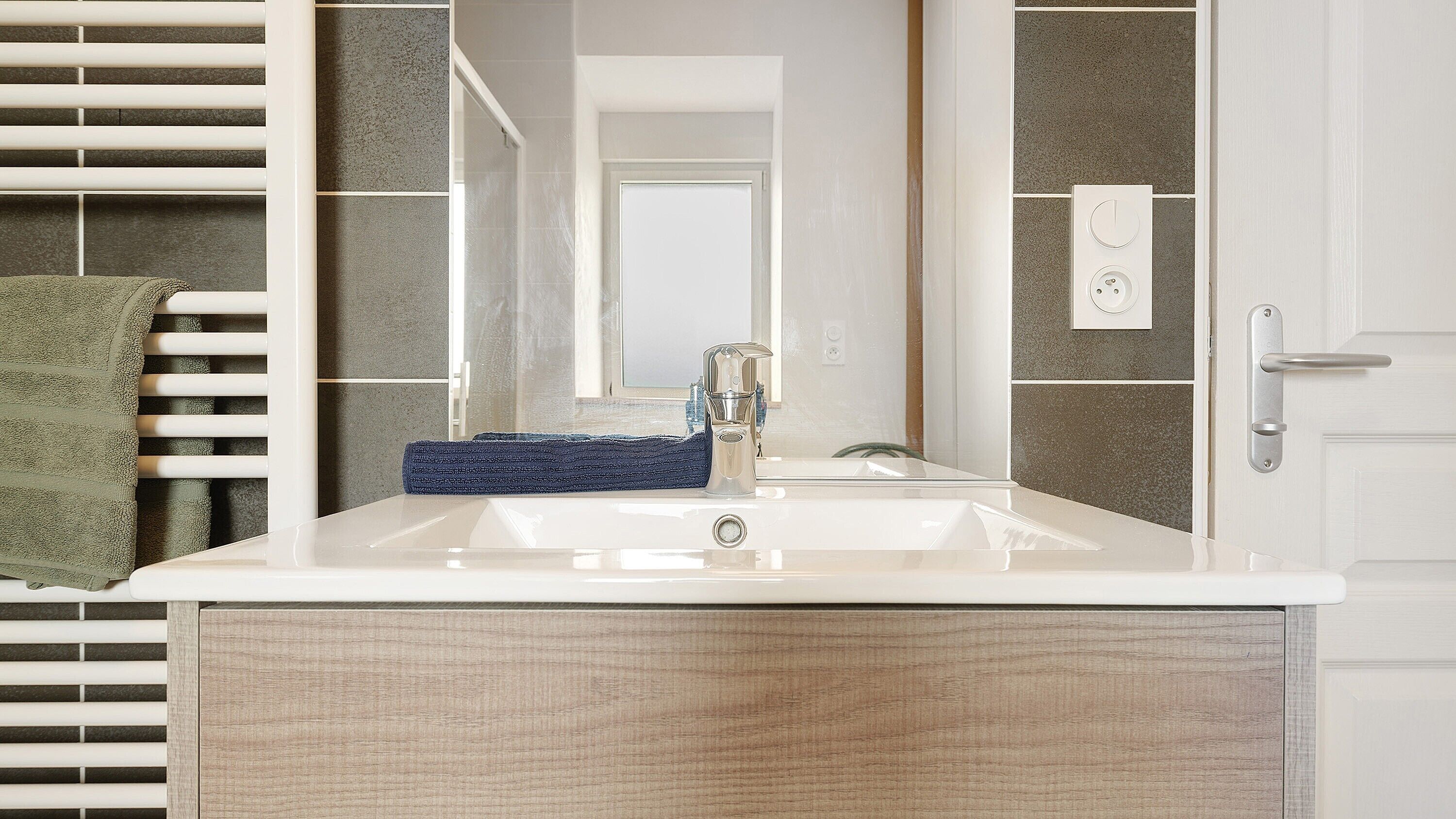 A bathroom with a white sink, a mirror, and a towel rack.
