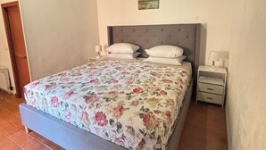 Een slaapkamer met een bed, twee nachtkastjes, een klein schilderij aan de wand en een houten plafond.