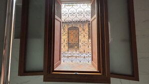 Uitzicht door een raam met een decoratieve ijzeren poort, een betegelde vloer en een houten deur.