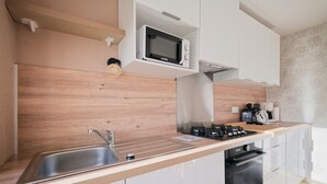 Ett modernt kök med inbyggd mikrovågsugn, diskho i rostfritt stål och en kaffemaskin.