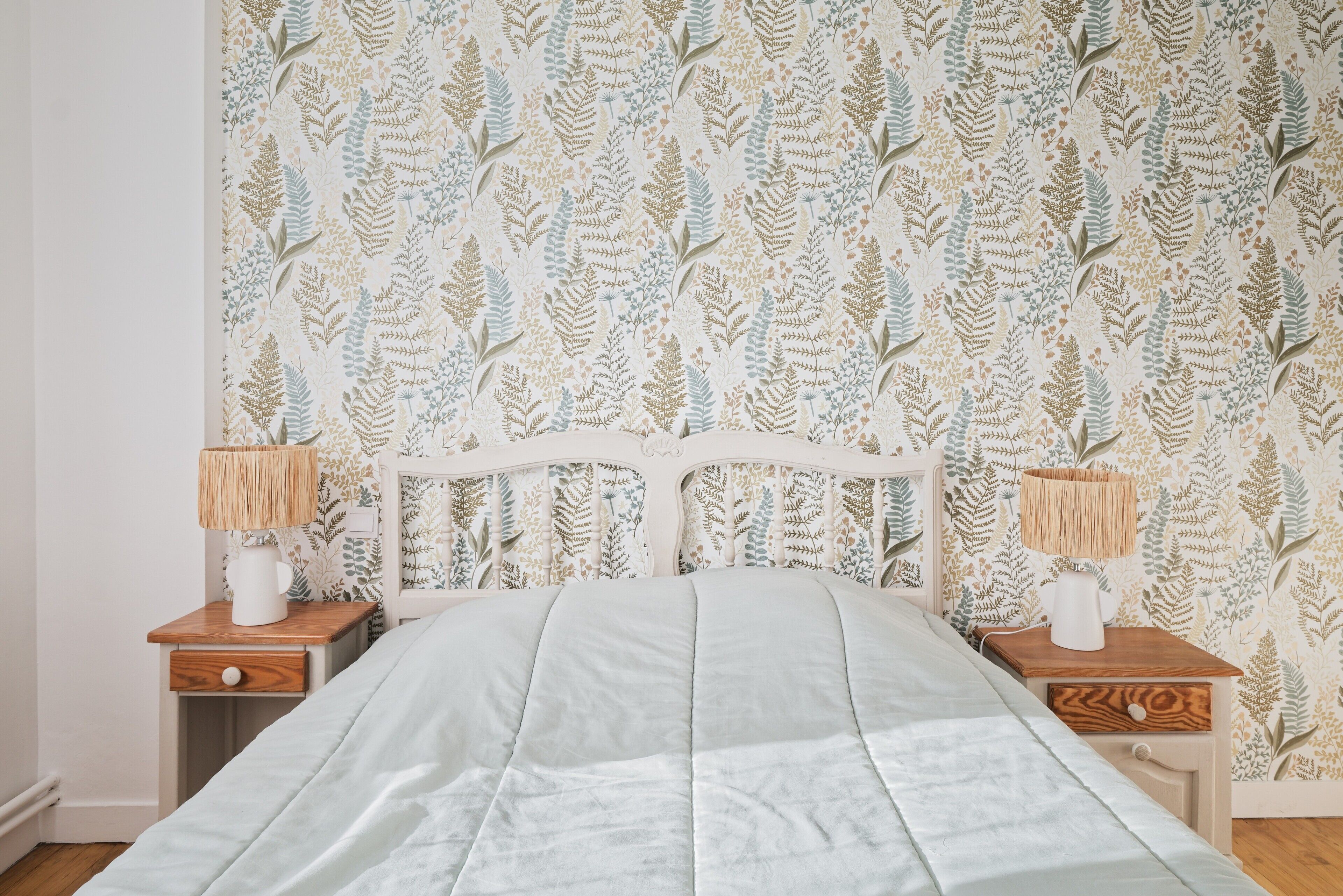 Una camera da letto con un letto, due comodini e carta da parati decorata.