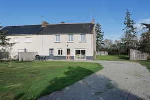 A two-story house with a gravel driveway and a lawn. - Holiday Home “La Clairière de Merlin” with Private Terrace, Garden and Wi-Fi (Neant sur yvel)
