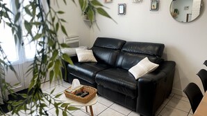Ein modernes Wohnzimmer mit einer schwarzen Ledersofa, einem kleinen runden Spiegel und gerahmten Bildern an der Wand.