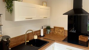 Eine moderne Küche mit weißen Schränken, einer schwarzen Dunstabzugshaube und einer Holz Arbeitsplatte.