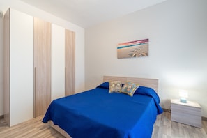 Une chambre à coucher comprenant un lit, une table de chevet, un tableau accroché au mur et une armoire.
