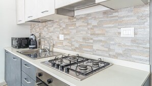 A modern kitchen with a gas stove, a microwave, and a coffee maker. - Apartment 'Mare Vista Piscina' with Sea View, Wi-Fi and Air Conditioning (Fontane Bianche)