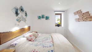 A bedroom with a wooden headboard, a bed with floral bedding, wall art, and a window with a view. - Lis Martagon Mountain Cottage, 3-Star Comfort Near Lifts (Font-Romeu-Odeillo-Via)