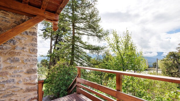 A wooden deck with stone walls, surrounded by greenery and trees. - Lis Martagon Mountain Cottage, 3-Star Comfort Near Lifts (Font-Romeu-Odeillo-Via)