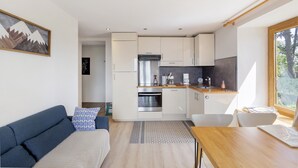 A modern kitchen with white cabinets, a stainless steel oven, and a wooden dining table. - Lis Martagon Mountain Cottage, 3-Star Comfort Near Lifts (Font-Romeu-Odeillo-Via)