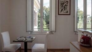 A dining area with a table set for two, a chair, and a red kettle on the counter. - Bohémien Rome (Roma)