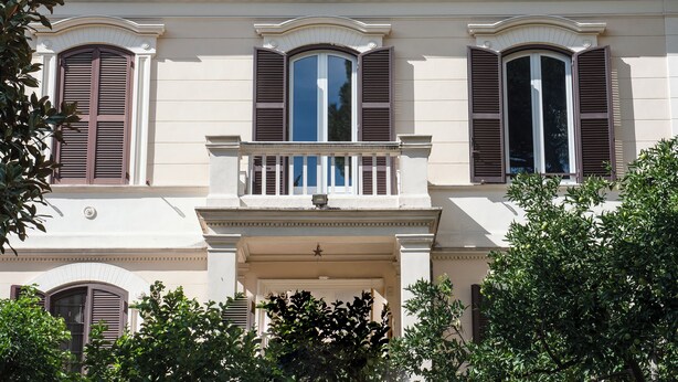 A classical building with three arched windows with shutters, a central balcony, and a star decoration above the entrance. - Bohémien Rome (Roma)