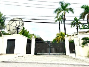 A gated entrance with a satellite dish, palm trees, and a clear sky. - Exotic 4-bedroom Villa at the beach in Ocho Rios (ocho Rios)