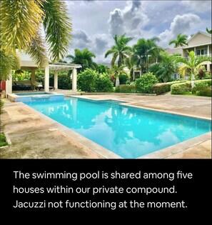 A swimming pool surrounded by lush greenery and palm trees, with a pergola and outdoor seating area. - Exotic 4-bedroom Villa at the beach in Ocho Rios (ocho Rios)