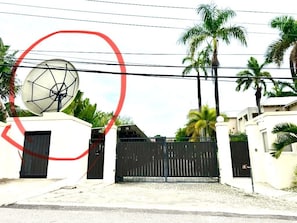 A gated residential area with a satellite dish, palm trees, and a clear sky. - Exotic 4-bedroom Villa at the beach in Ocho Rios (ocho Rios)