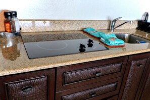 A kitchen with a granite countertop, a stove, and a sink.