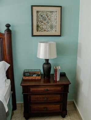 A wooden nightstand with a lamp, a framed picture, a basket, and books.