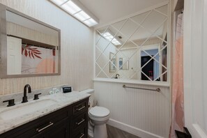 A bathroom with a white vanity, a black faucet, a toilet, and a window with a white grid design.