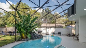 An indoor swimming pool with a glass ceiling, surrounded by lounge chairs and a stone wall. - Lakefront Mansion with Pool and Pilates (Orlando)