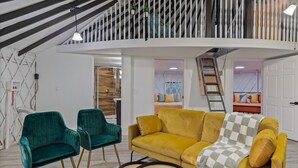 A modern living room with a yellow sofa, teal chairs, and a patterned rug. - Florida Yurt Escape • Nature + Comfort (Kissimmee)