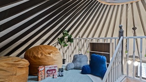 A cozy, circular tent-style room with a bed, bean bags, and a small table with a board game. - Florida Yurt Escape • Nature + Comfort (Kissimmee)