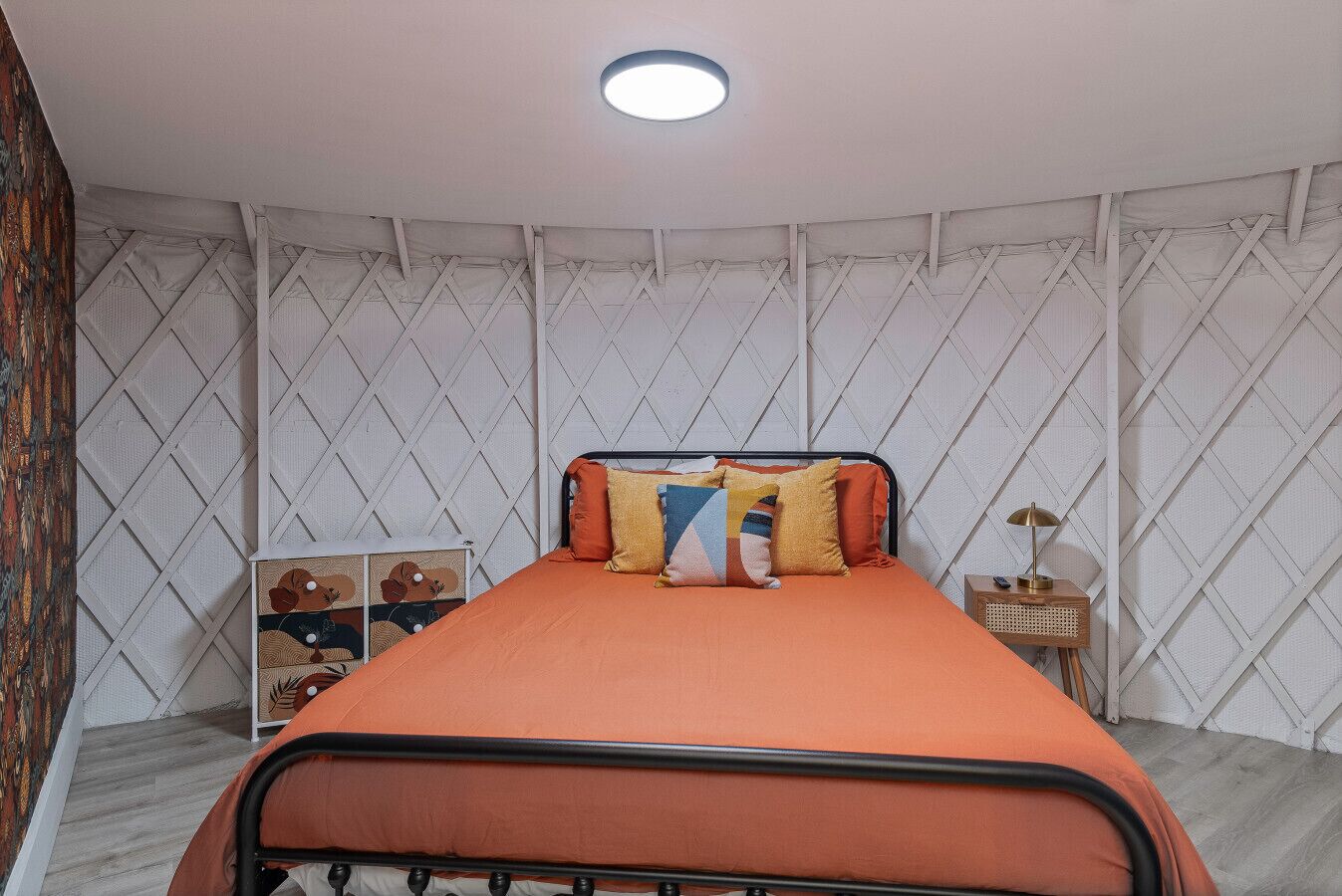 A bedroom with a bed, a nightstand, and a wall with a diamond pattern.
