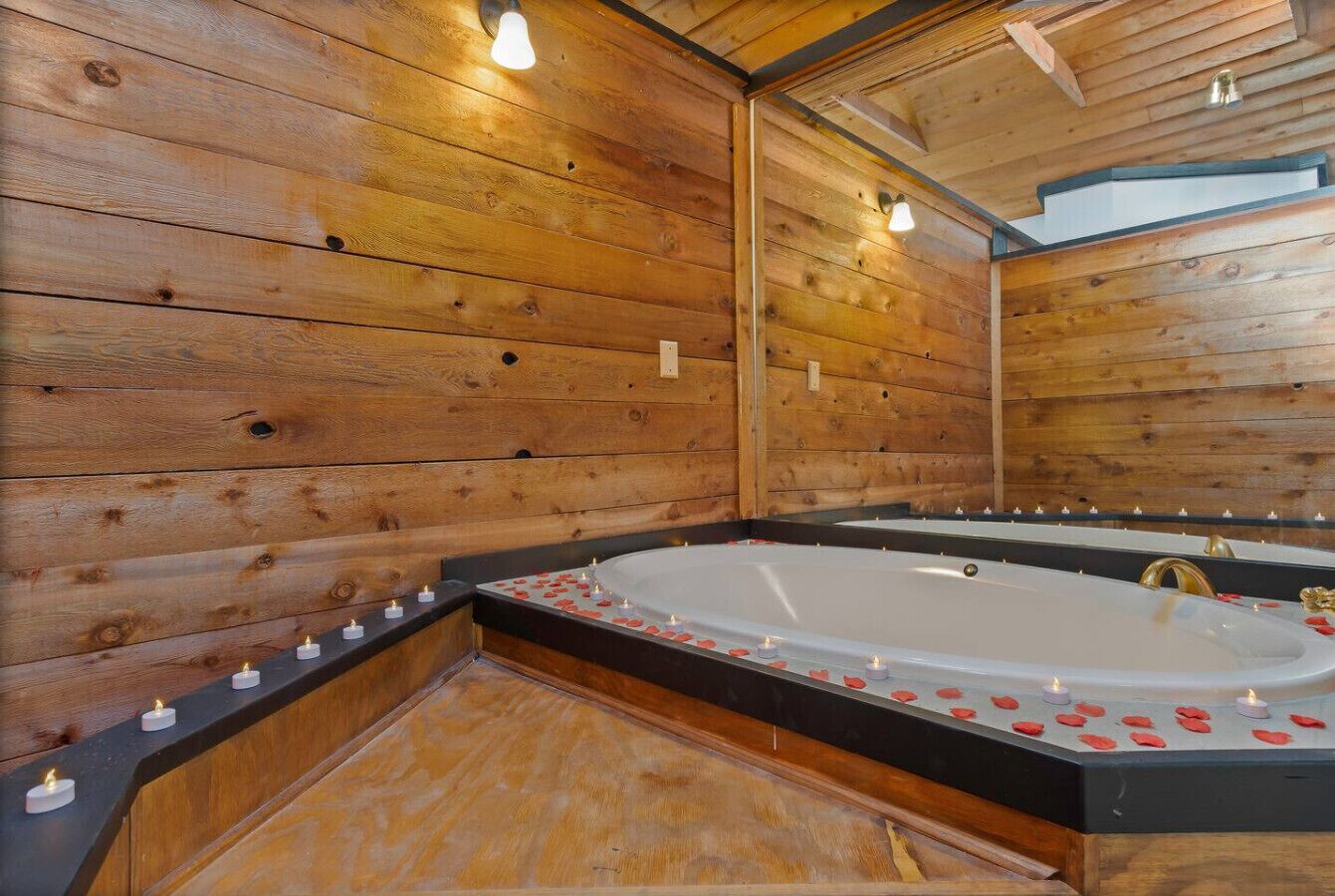 A wooden cabin interior with a large oval bathtub, candles, and a mirror.