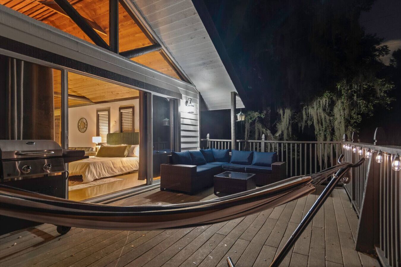A deck with a hammock, a sofa, and a grill.