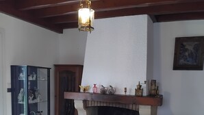 A living room with a fireplace, a leather armchair, a glass cabinet with decorative items, and a wooden ceiling. - House 115m² with swimming pool, 20 min from Bordeaux center Tram 500m. (Eysines)