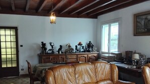 A living room with a brown leather sofa, wooden ceiling beams, and a dining area with a table and chairs. - House 115m² with swimming pool, 20 min from Bordeaux center Tram 500m. (Eysines)